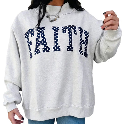 Woman wearing light gray oversized crewneck sweatshirt with FAITH lettering across the chest